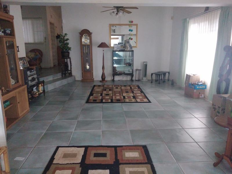 Spacious living area featuring neutral tiled flooring and a ceiling fan, offering a versatile layout for comfortable family living.