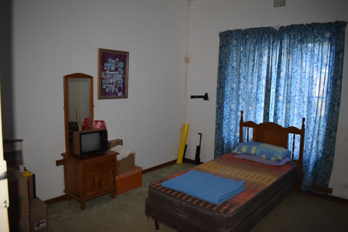 A bedroom featuring carpeted flooring and a window with curtain rails, offering a functional space ready for modernization and personal updates.