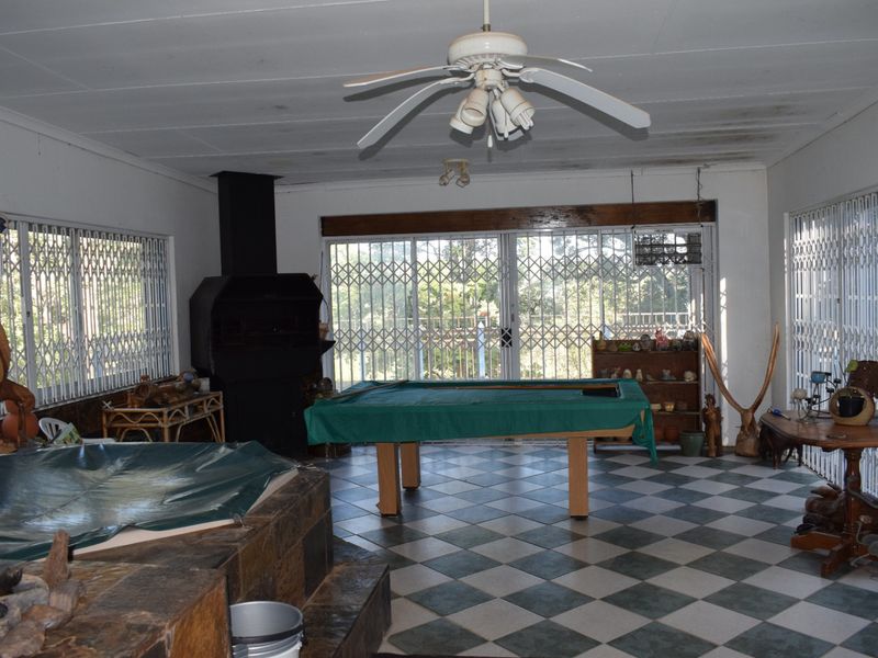Spacious living area featuring a built-in fireplace, tiled flooring, and sliding doors with security gates, offering potential for a modern entertainment space.