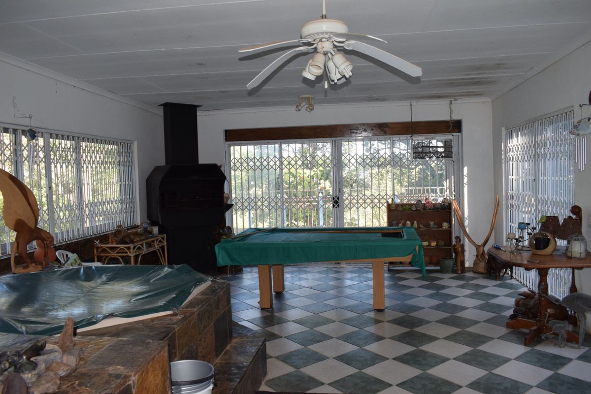 Spacious living area featuring a built-in fireplace, tiled flooring, and sliding doors with security gates, offering potential for a modern entertainment space.