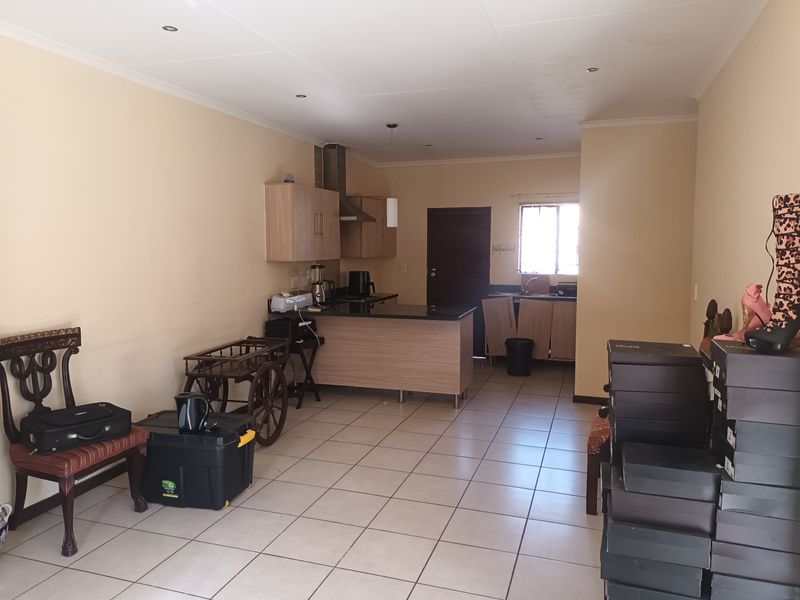 Open plan kitchen and living area featuring tiled flooring, built-in cabinetry, and a central kitchen island with an extractor fan.