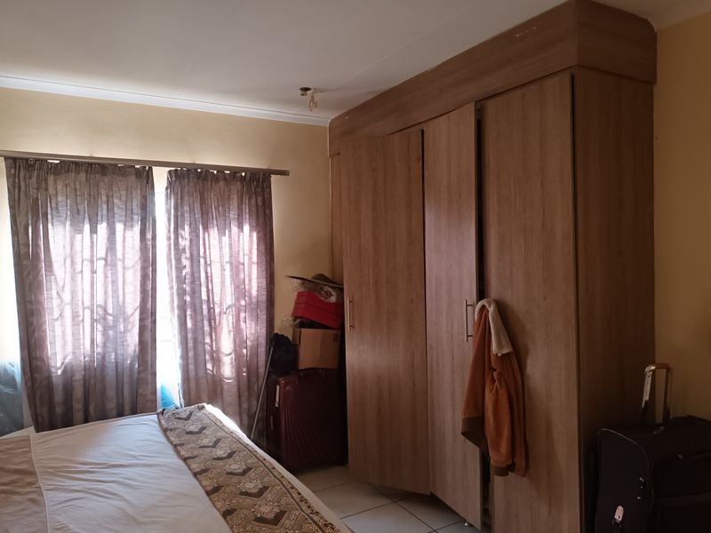 A bedroom featuring built-in wooden wardrobes and tiled flooring, offering functional storage space.
