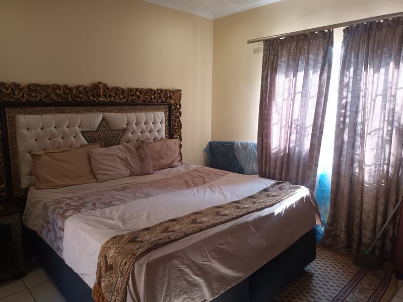 A bedroom featuring neutral wall tones and a window fitted with a curtain rod.