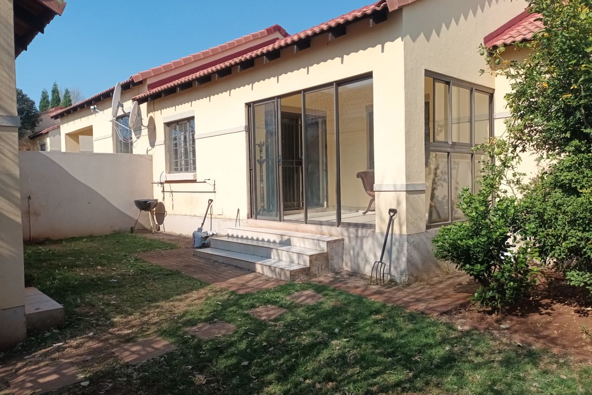Rear view of the townhouse featuring a paved patio area, sliding glass doors, and a small private garden space.