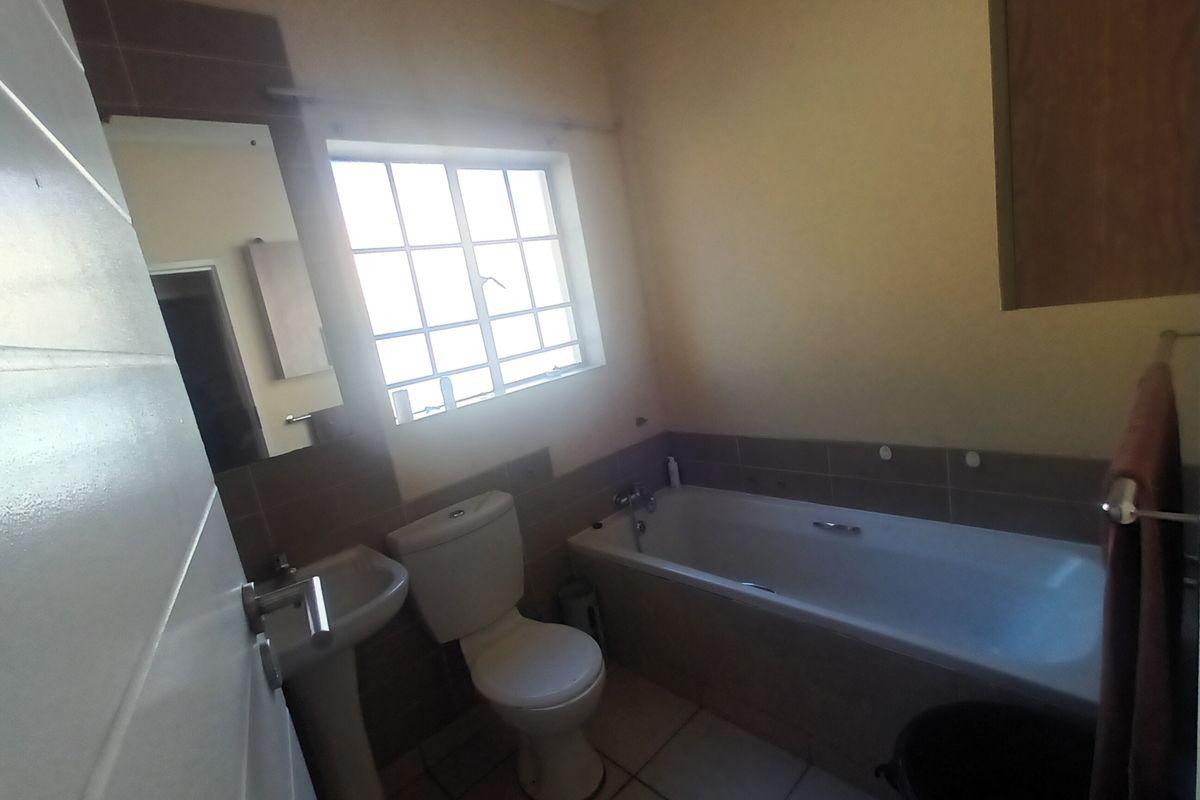 A functional bathroom featuring a pedestal basin, standard toilet, and a bathtub with tiled splashbacks and flooring.