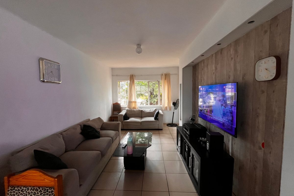 A comfortable living room featuring tiled flooring and a wood-look feature wall, providing a neutral base for modern interior design updates.