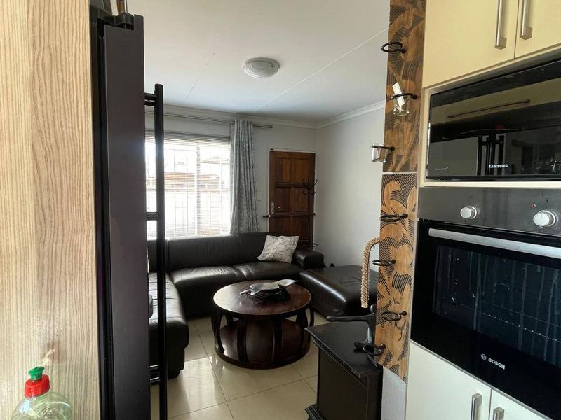 Open plan kitchen and living area featuring tiled flooring, built-in oven, microwave, and cabinetry, creating a functional and connected living space.