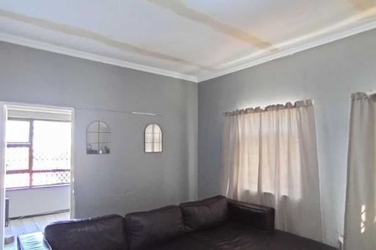 A living room featuring grey walls and ceiling water damage, requiring maintenance and cosmetic updates to improve the overall condition of the space.