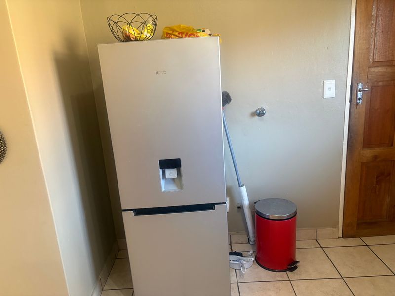 A kitchen area featuring tiled flooring and a dedicated water connection point for appliances.