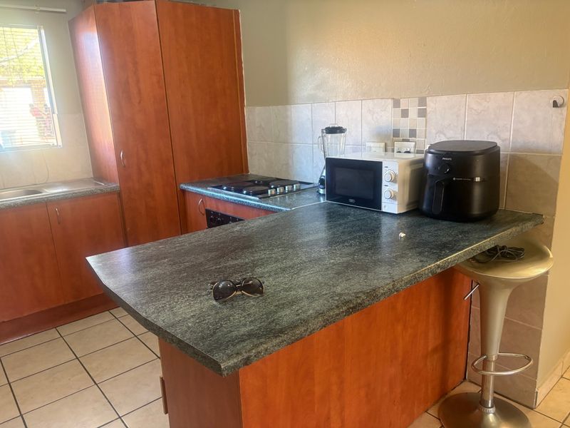 A functional kitchen featuring laminate cabinetry, tiled backsplash, built-in gas hob, oven, and a breakfast bar counter.