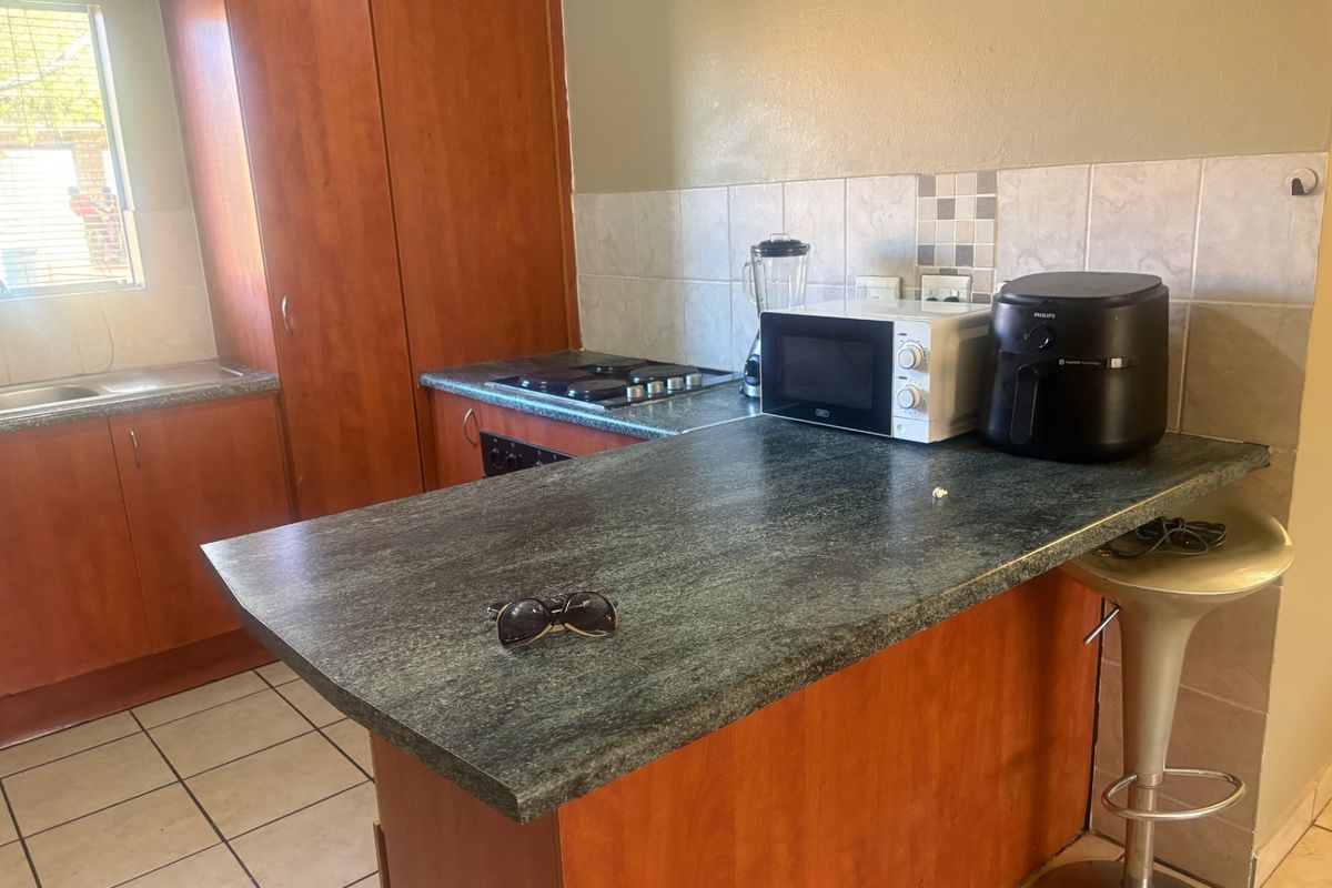 A functional kitchen featuring laminate cabinetry, tiled backsplash, built-in gas hob, oven, and a breakfast bar counter.
