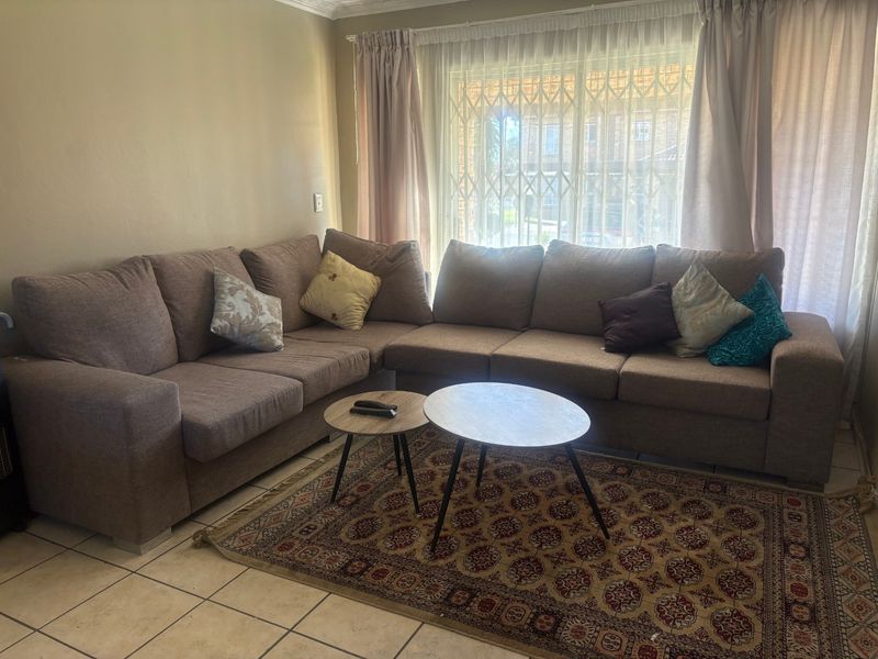 A living room featuring ceramic floor tiles, a large window with a security gate, and decorative ceiling cornicing.