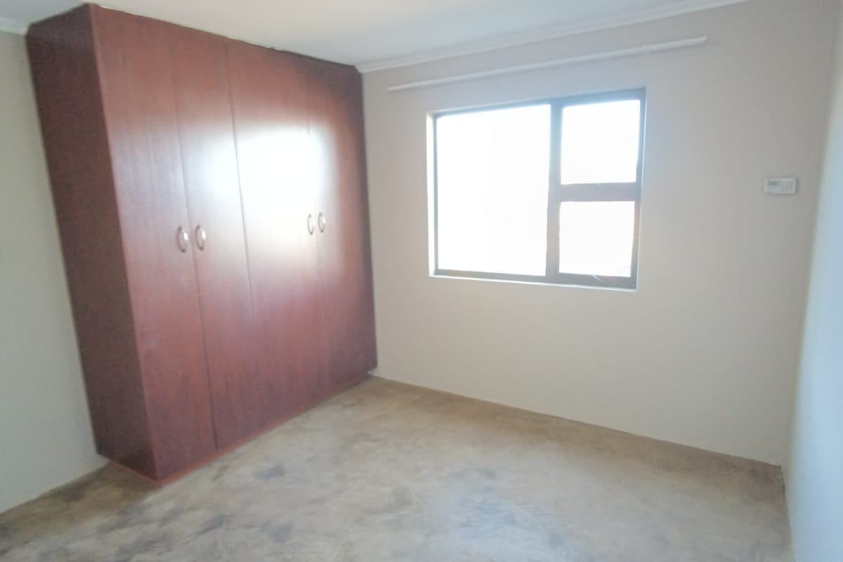 A vacant bedroom featuring built-in wooden cupboards and a window, providing a blank canvas for personalization.