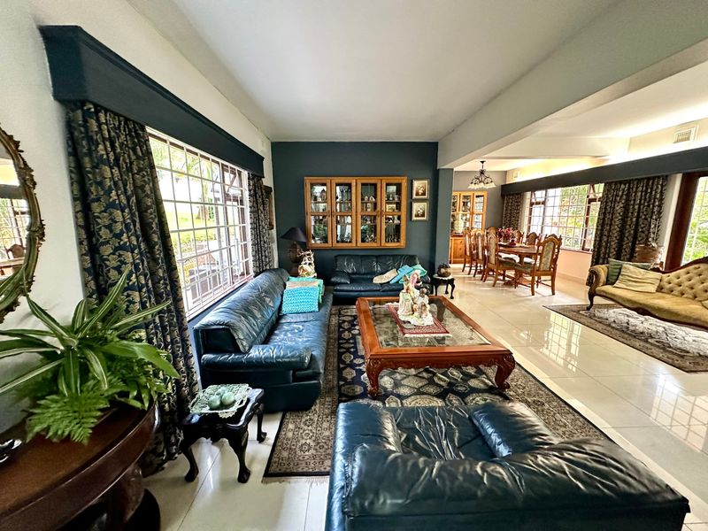 Spacious open-plan living and dining area featuring tiled flooring, large windows, and a built-in display cabinet, offering a versatile layout for family living.