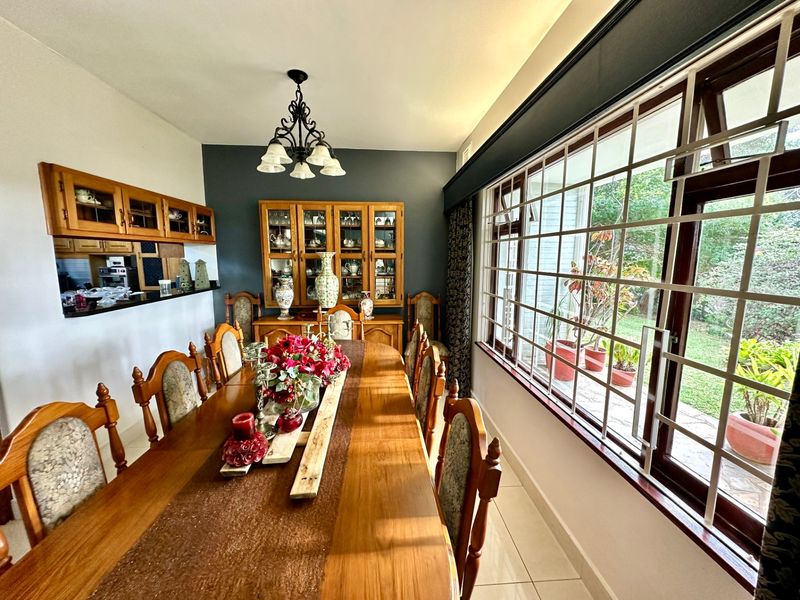 Dining room featuring tiled flooring, built-in wooden cabinetry, and large windows with security bars overlooking the garden.