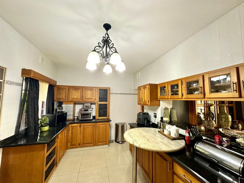 A functional kitchen featuring traditional wooden cabinetry, granite countertops, tiled flooring, and a breakfast bar, offering ample storage and workspace.