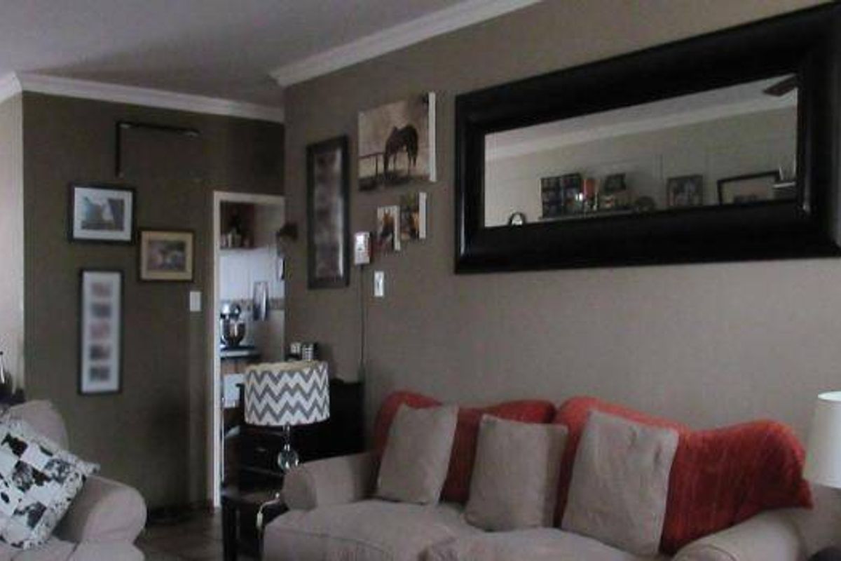 A living room area featuring neutral wall tones, crown molding, and a cased opening leading to an adjacent space.