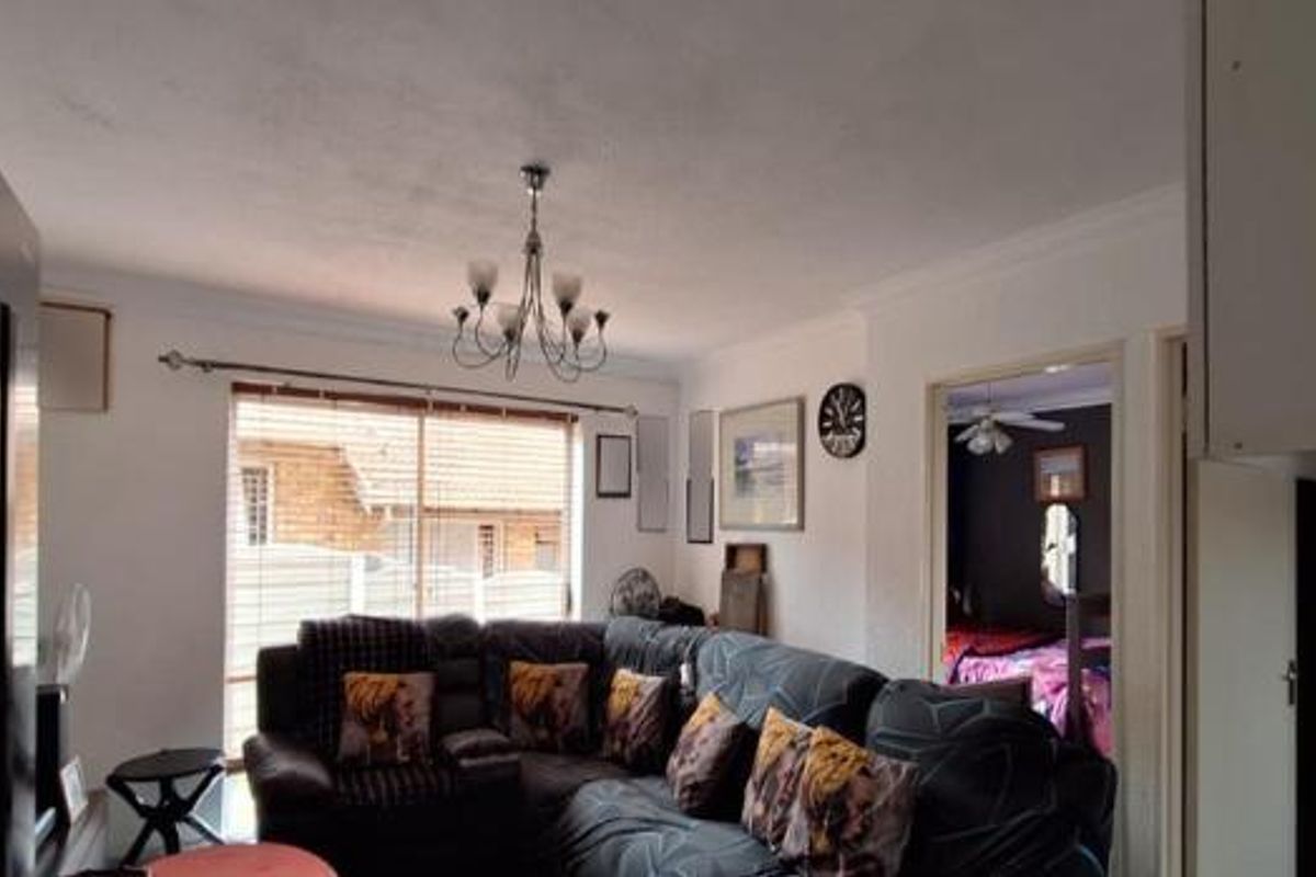 A living room area featuring a ceiling chandelier, coved cornices, and a sliding glass door providing access to the exterior.