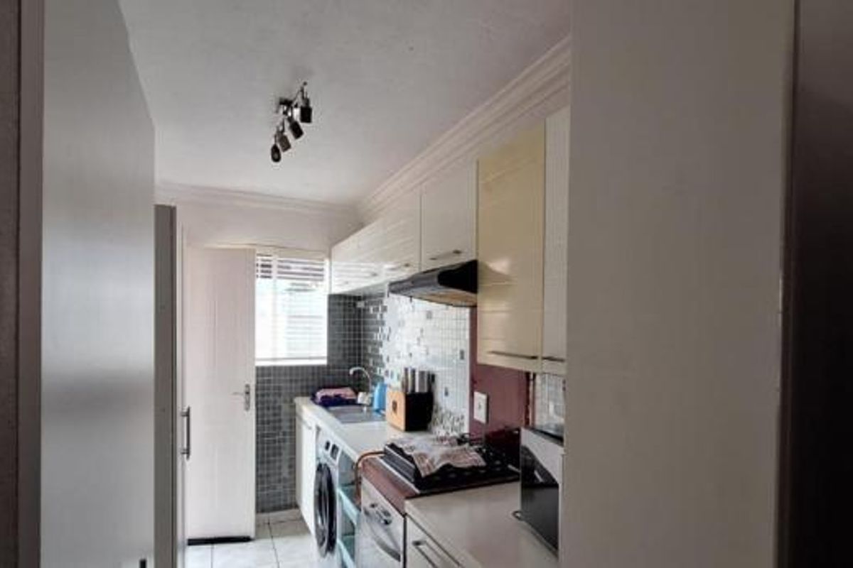 A functional kitchen featuring built-in cabinetry, a tiled backsplash, integrated oven, and hob, providing a practical workspace for daily cooking needs.