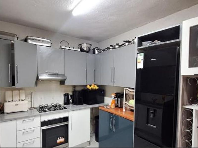 A functional kitchen featuring grey and white cabinetry, a gas hob with extractor fan, built-in oven, and a dedicated wine storage section.