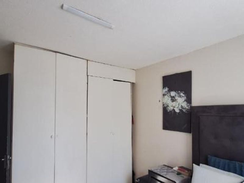 A bedroom featuring built-in cupboards and a ceiling-mounted light fixture, offering functional storage space.
