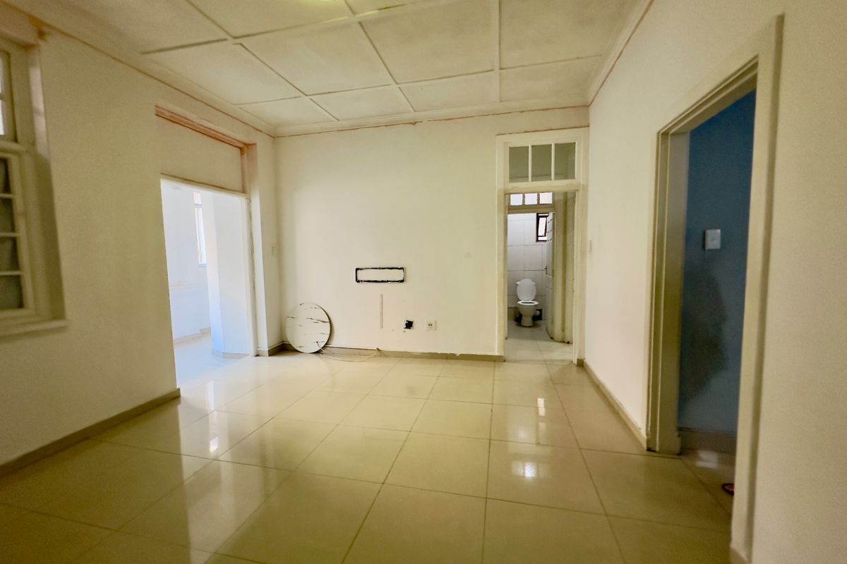 An empty living area featuring tiled flooring and neutral walls, providing a blank canvas for interior design and renovation.