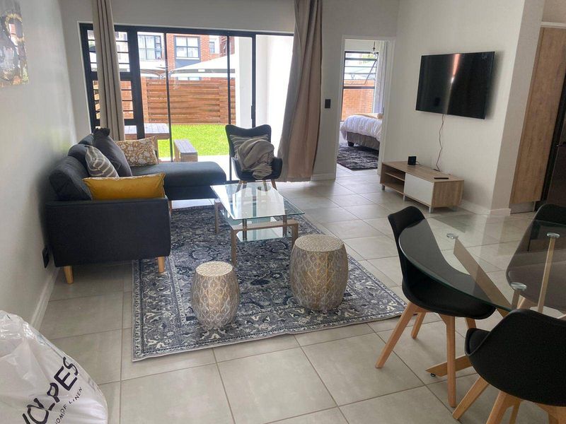 Open-plan living and dining area featuring tiled flooring and large sliding glass doors that provide access to the outdoor patio and garden.