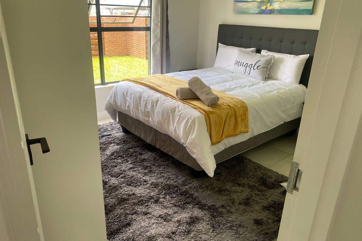 A well-maintained bedroom featuring tiled flooring and a large window providing natural light and a view of the exterior garden area.