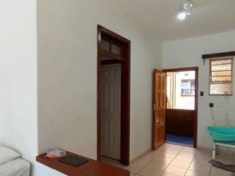 A functional hallway area featuring tiled flooring, wooden door frames, and access to an adjacent room and exterior space.