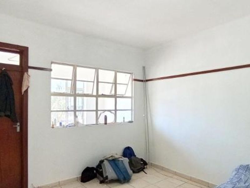 A vacant bedroom featuring a timber door, steel-framed window, and traditional picture rail, offering a blank canvas for renovation and interior design updates.