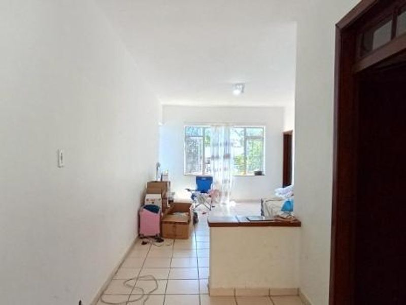 An open-plan living area featuring tiled flooring and a low partition wall, offering a blank canvas for potential interior design and renovation.