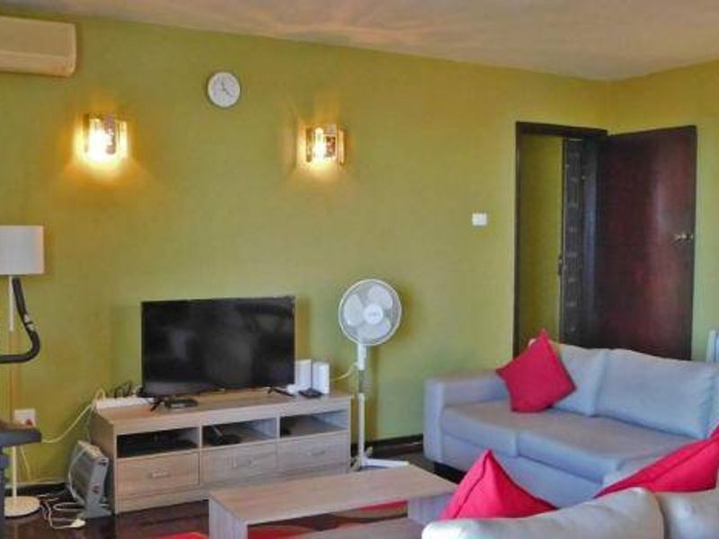 A living room featuring olive green walls, wall-mounted lighting, a split-system air conditioner, and a radiator heater.