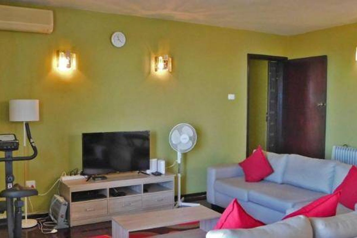 A living room featuring olive green walls, wall-mounted lighting, a split-system air conditioner, and a radiator heater.