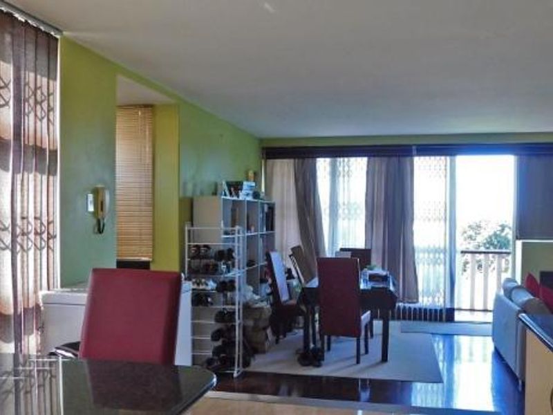 Open-plan living and dining area featuring laminate flooring, kitchen cabinetry with granite countertops, and large sliding glass doors leading to a balcony.