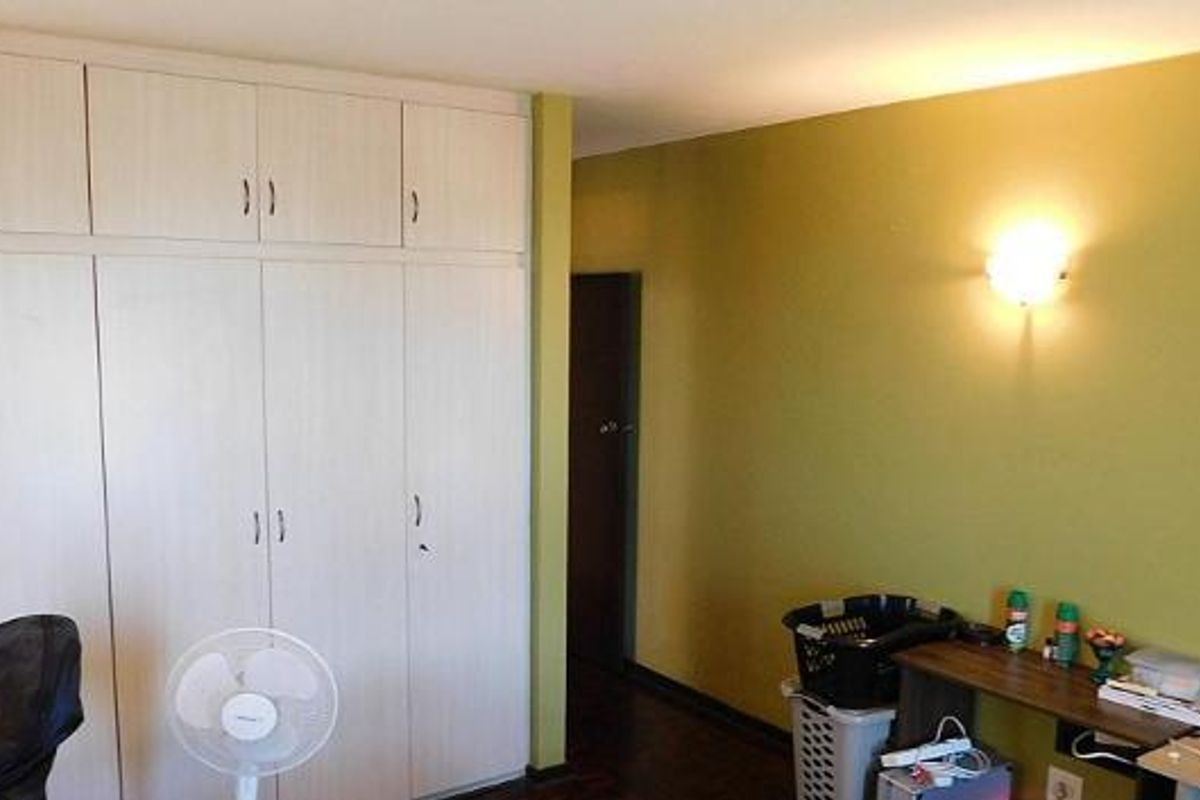 A bedroom featuring extensive floor-to-ceiling built-in cupboards and a wall-mounted light fixture, offering ample storage space.