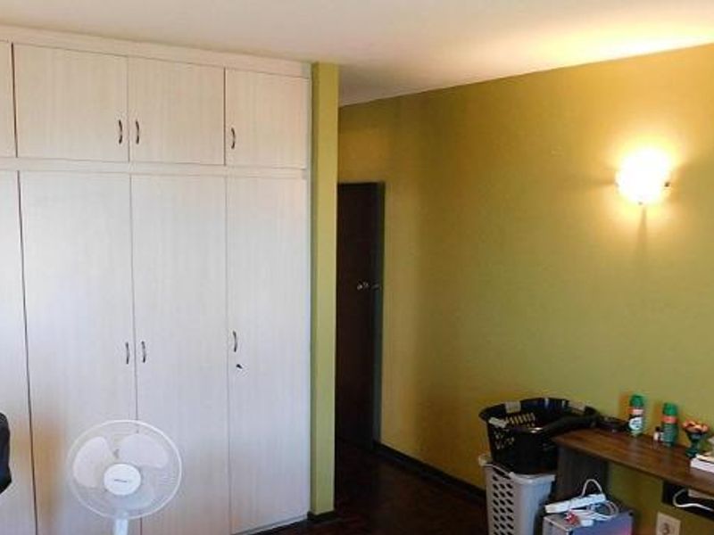 A bedroom featuring extensive floor-to-ceiling built-in cupboards and a wall-mounted light fixture, offering ample storage space.
