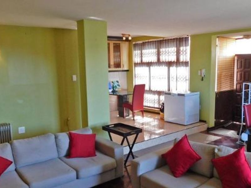 Spacious open-plan living and dining area featuring large windows with security gates and integrated kitchen cabinetry.