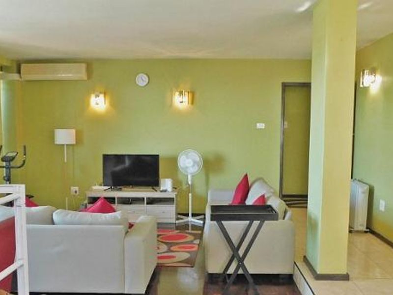 Open-plan living area featuring tiled flooring, wall-mounted air conditioning, and neutral wall finishes, providing a versatile space for relaxation and dining.