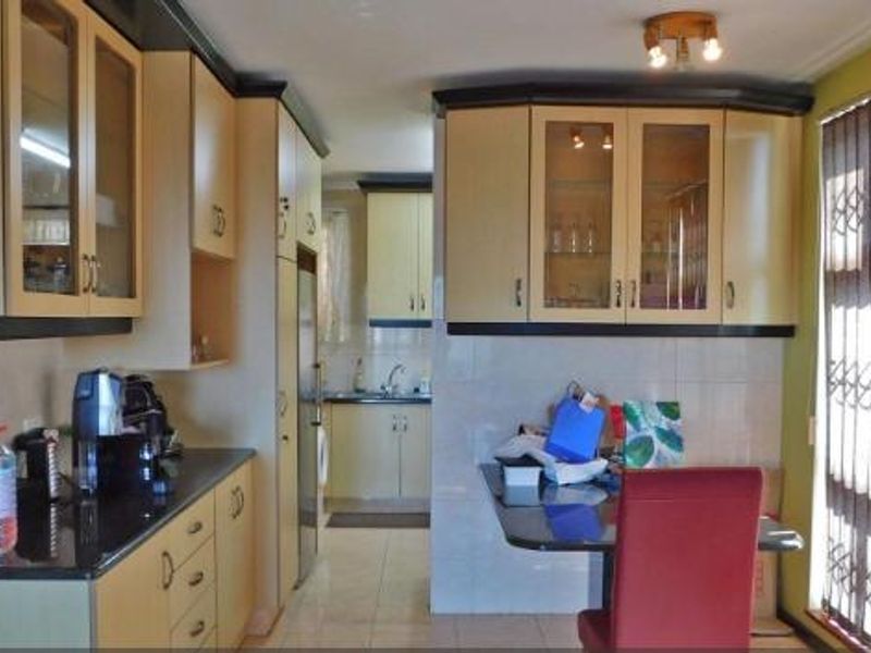 A functional kitchen featuring built-in cabinetry, tiled backsplash, and tiled flooring, offering a practical layout with ample storage space.