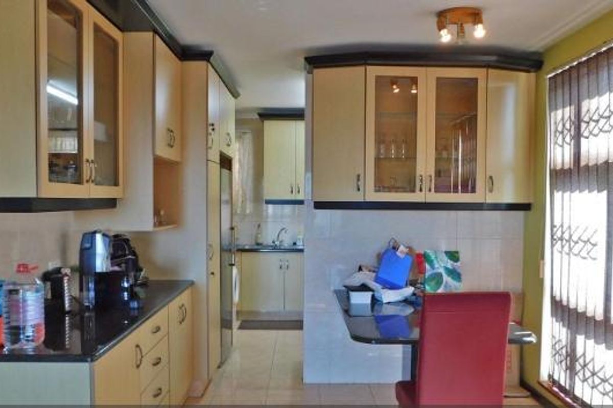 A functional kitchen featuring built-in cabinetry, tiled backsplash, and tiled flooring, offering a practical layout with ample storage space.