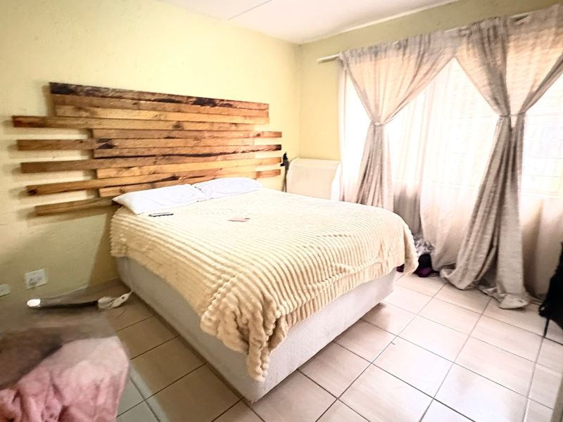 A bedroom featuring tiled flooring and curtain rails, currently requiring cosmetic updates to the wall finishes.