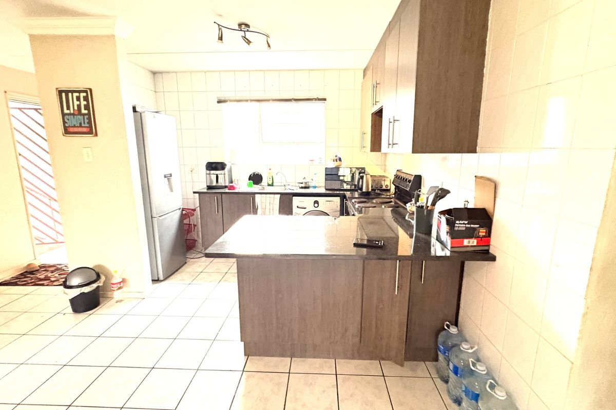 A functional kitchen featuring dark wood cabinetry, granite countertops, tiled backsplash, and tiled flooring, providing a practical workspace with integrated appliances.