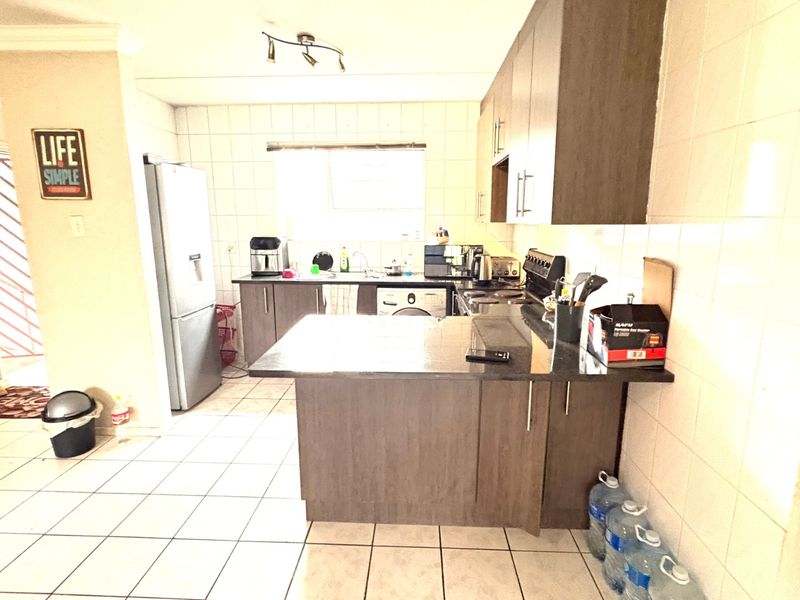 A functional kitchen featuring dark wood cabinetry, granite countertops, tiled backsplash, and tiled flooring, providing a practical workspace with integrated appliances.