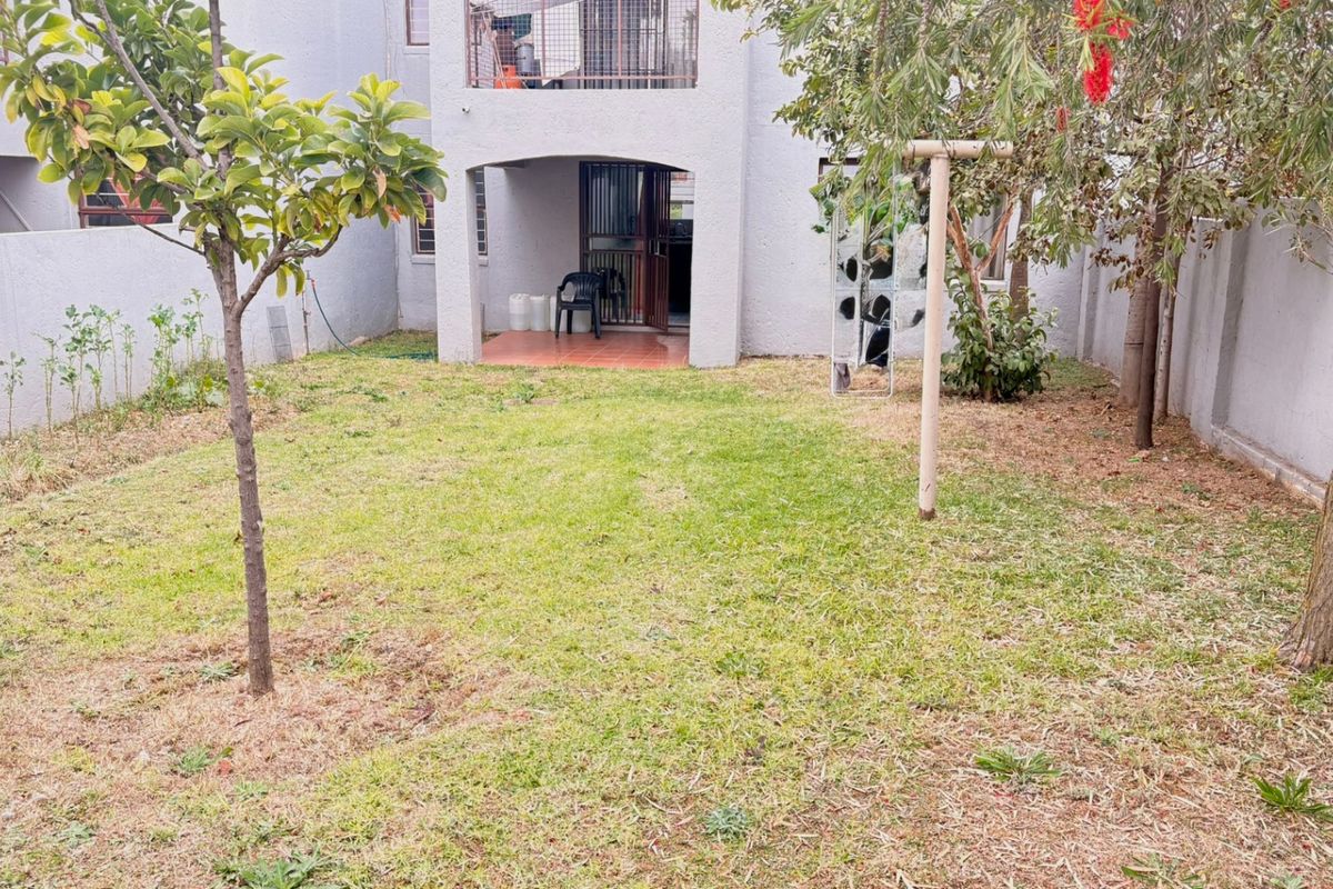 A private rear garden featuring a lawn area and a covered patio with access to the apartment interior.
