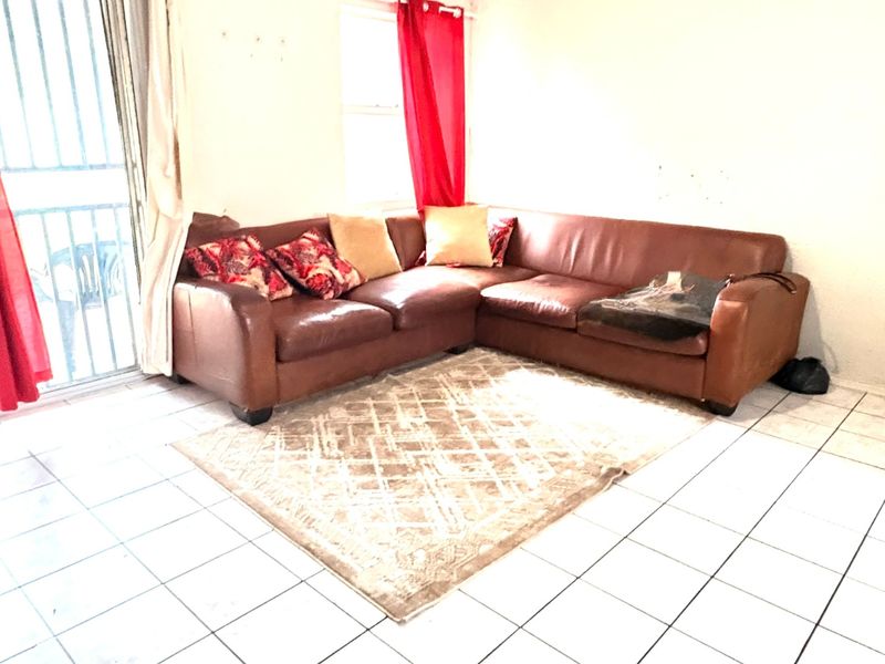 Living room featuring white tiled flooring and a sliding glass door with security gate access to the exterior.