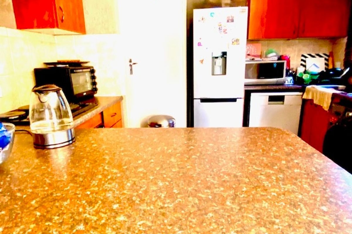 A functional kitchen featuring laminate countertops, built-in cabinetry, and a tiled backsplash, providing a practical workspace for daily meal preparation.