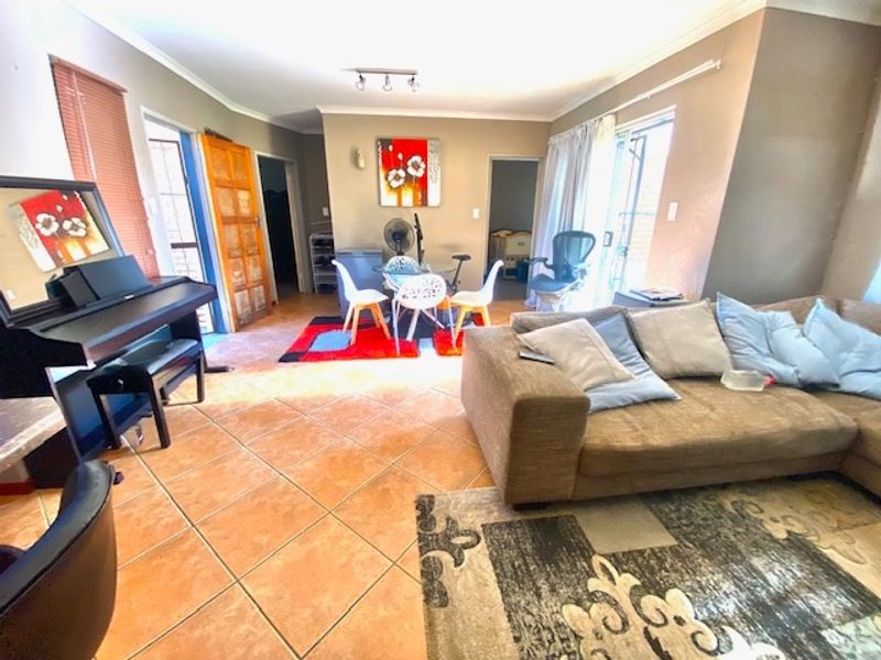 Open plan living area featuring ceramic floor tiles, track lighting, and sliding glass door access to the exterior.