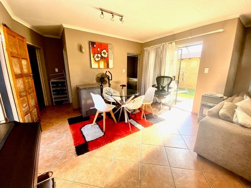 Open plan living and dining area featuring ceramic floor tiles, coved ceilings, and direct access to the rear patio through a sliding glass door.