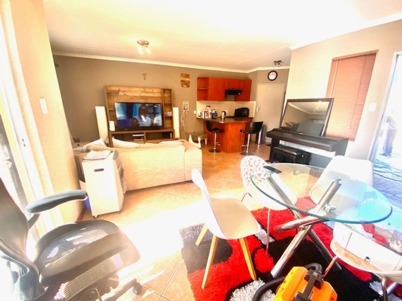 Open-plan living and dining area featuring tiled floors, a breakfast bar kitchen, and direct access to the outdoor space via a sliding door.