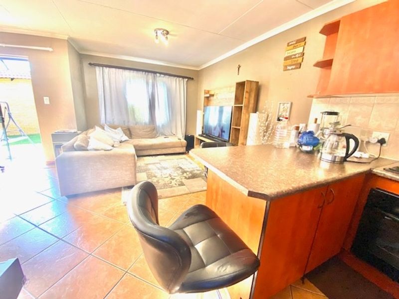 Open-plan living area featuring a kitchen with island, tiled flooring, and direct access to an outdoor patio space.